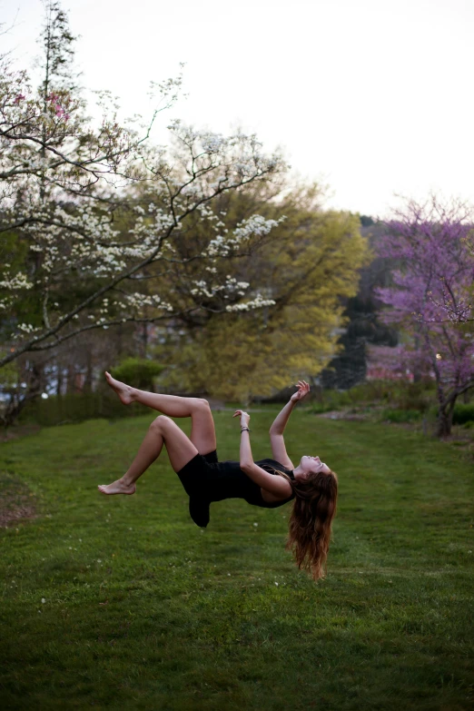 a woman upside down on a lush green field