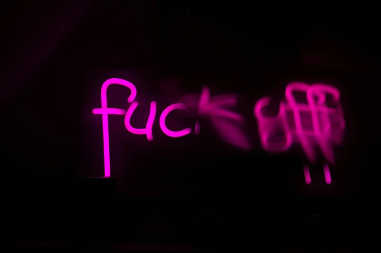a neon pink neon sign and some letters on a black background