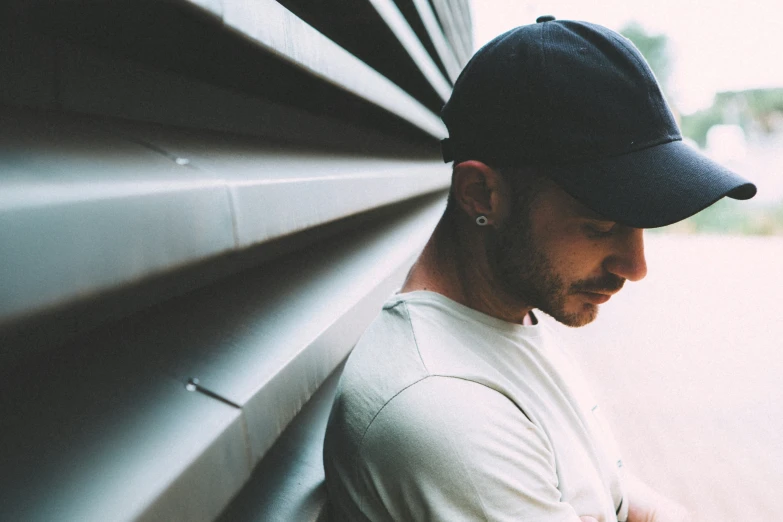 a man with ear piercings, a baseball hat and a baseball cap