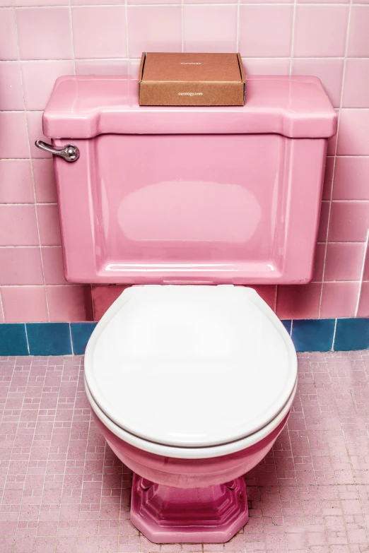 a pink toilet in a bathroom with white tiles