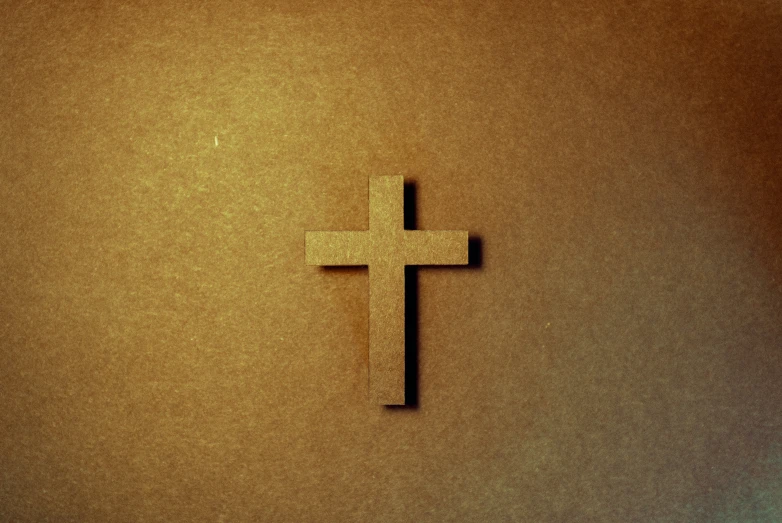 a close up view of a cross on a brown wall