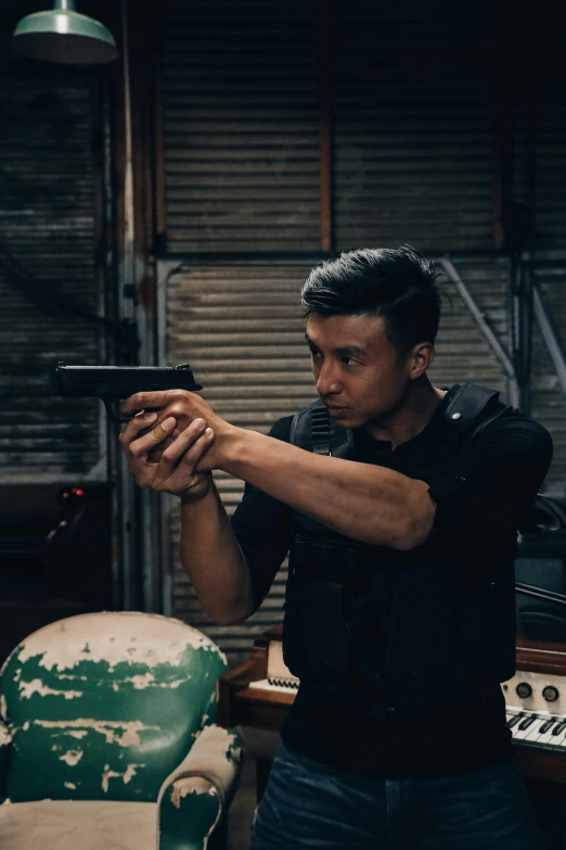 an asian man holding a gun in his right hand