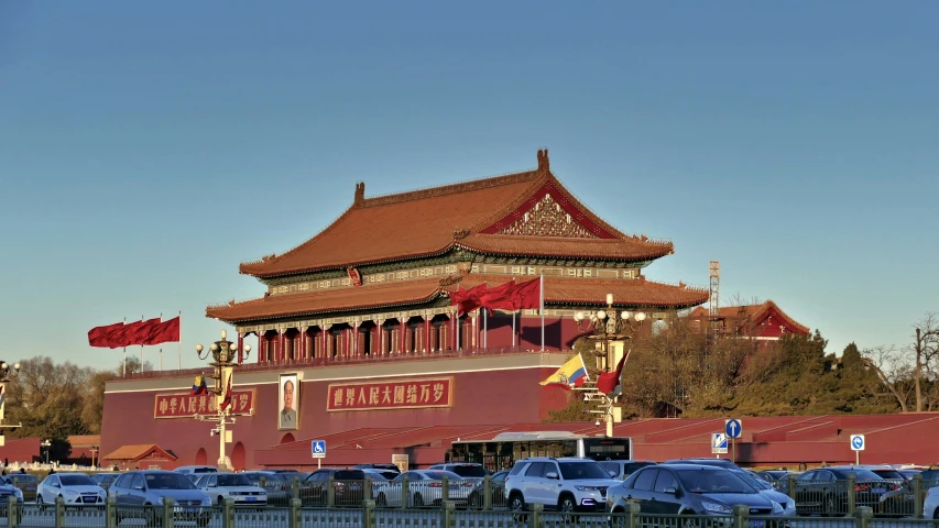 a chinese building with many flags and cars parked in front