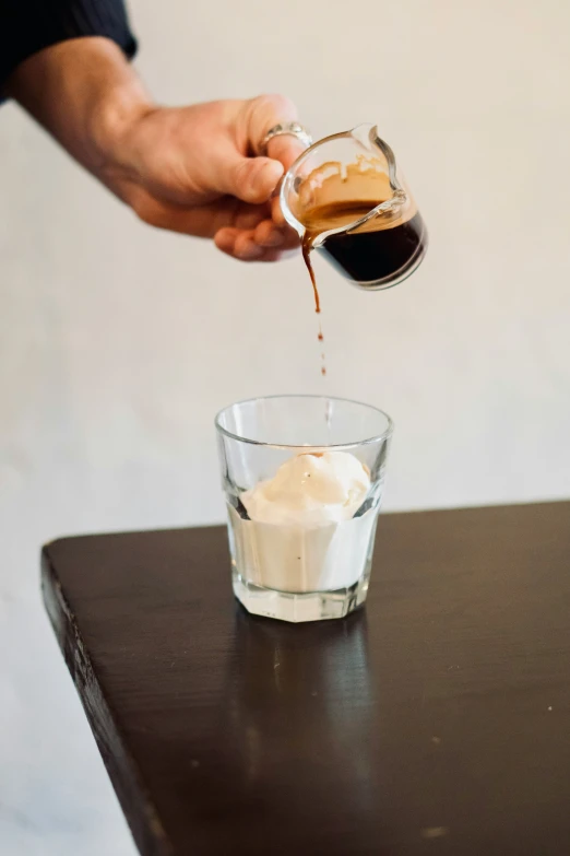 the coffee is being poured into a small glass