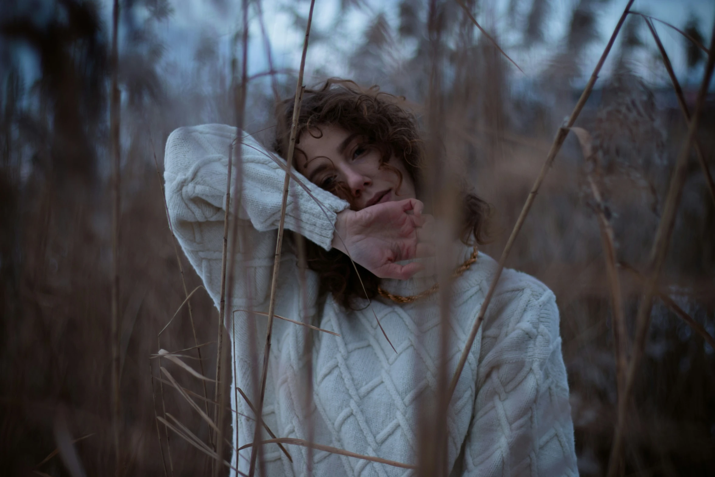 the woman is hiding her face behind tall grass