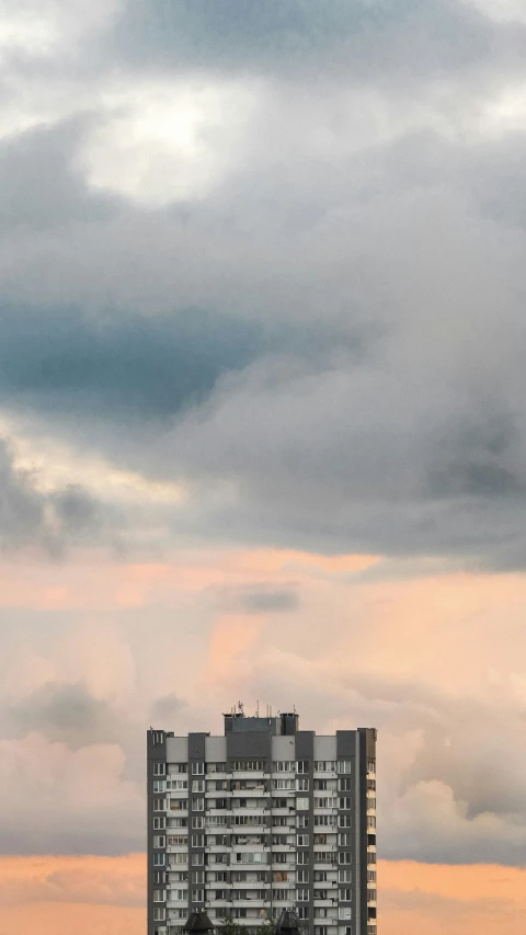 a very tall building with lots of windows against a cloudy sky