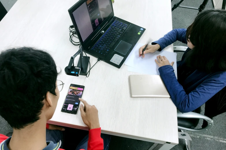 two people sitting at a table with computers