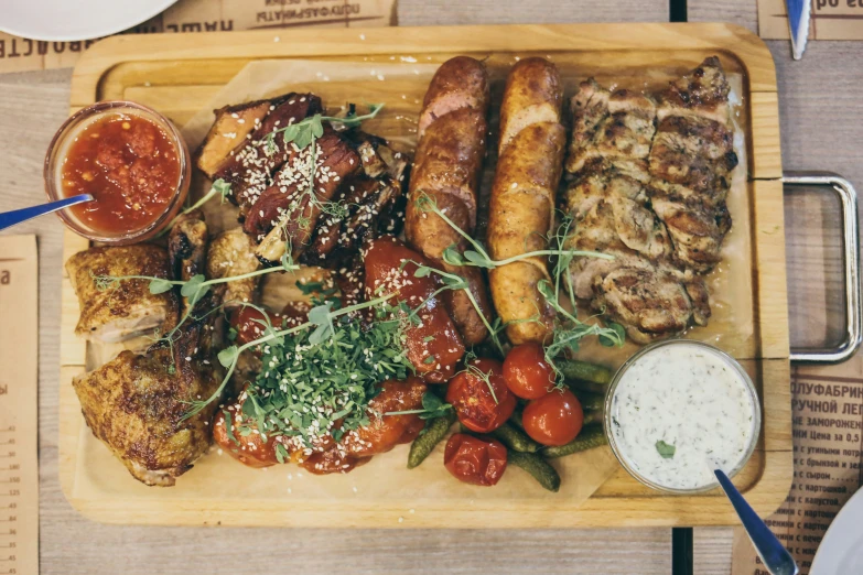 a platter of meat, sausage and vegetables sits on top of a table