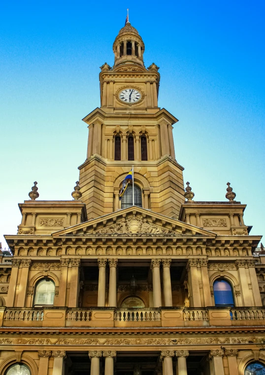 a clock tower atop an old building and a flag in the foreground