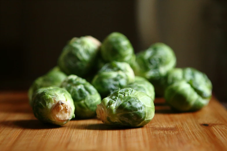 several brussel sprouts sit on a wooden surface