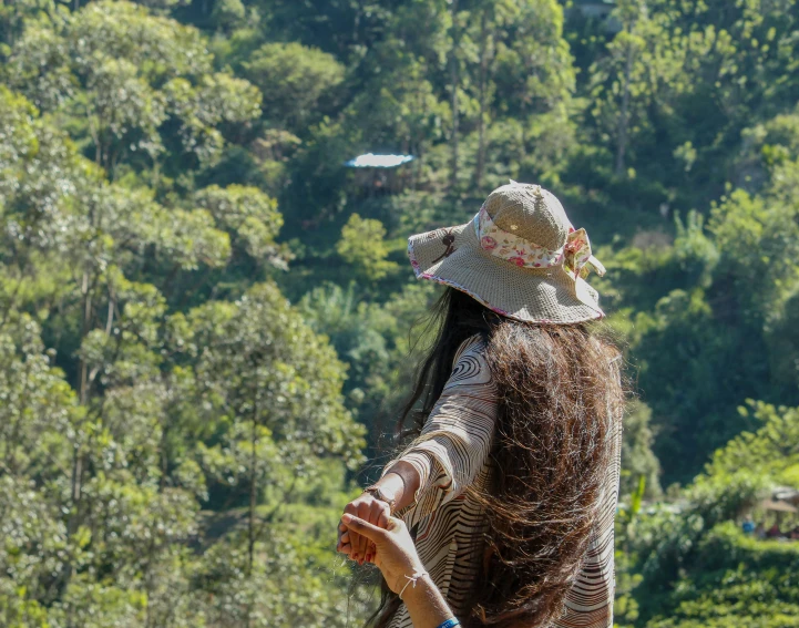 the back of a woman's head standing in front of trees