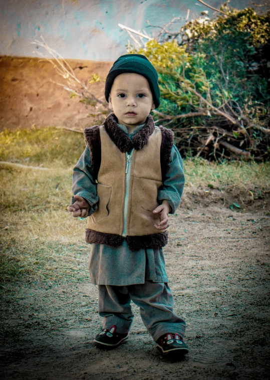 a small boy standing on top of a dirt field