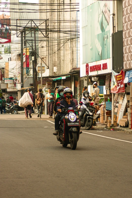 people riding on motorcycles down the street in a city