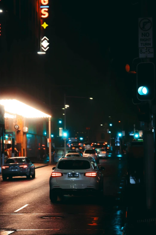 a city street at night with cars parked on the side of the road