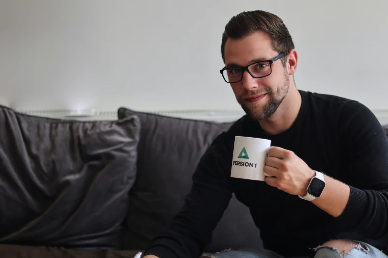 a man wearing glasses and holding a mug