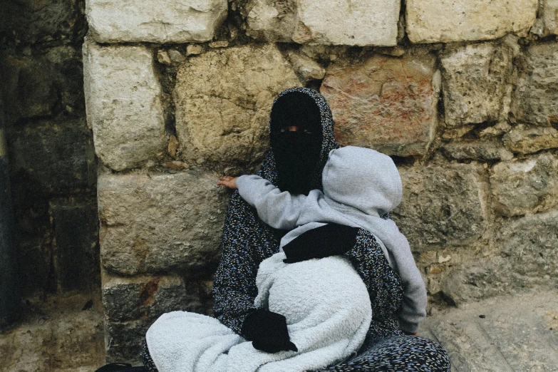 a person sitting next to a stone wall