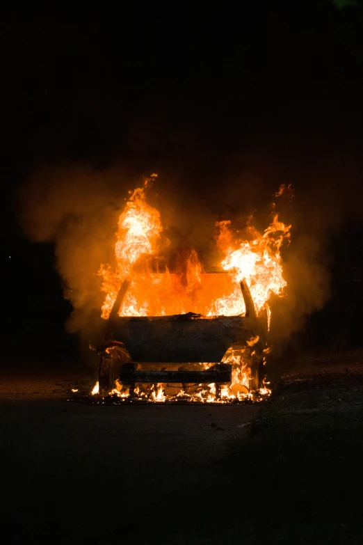 a van is burning in the dark on some kind of lot