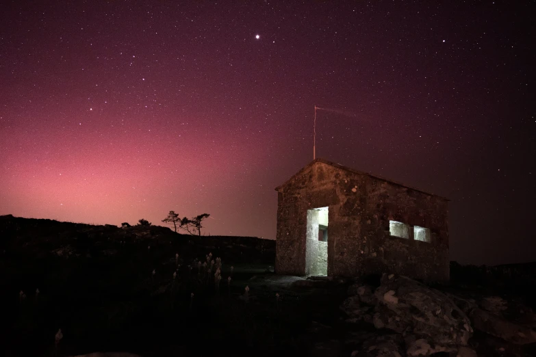 a small shack sits in the dark under the night sky