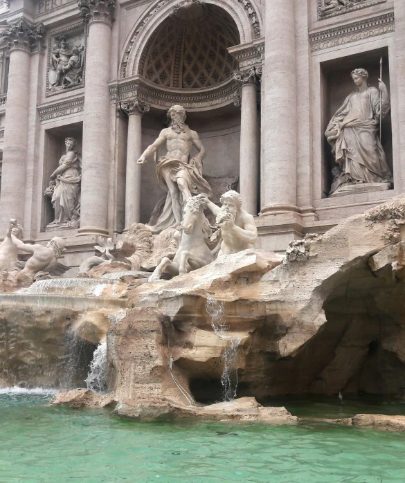 sculptures on the side of a building with water coming out of the sides