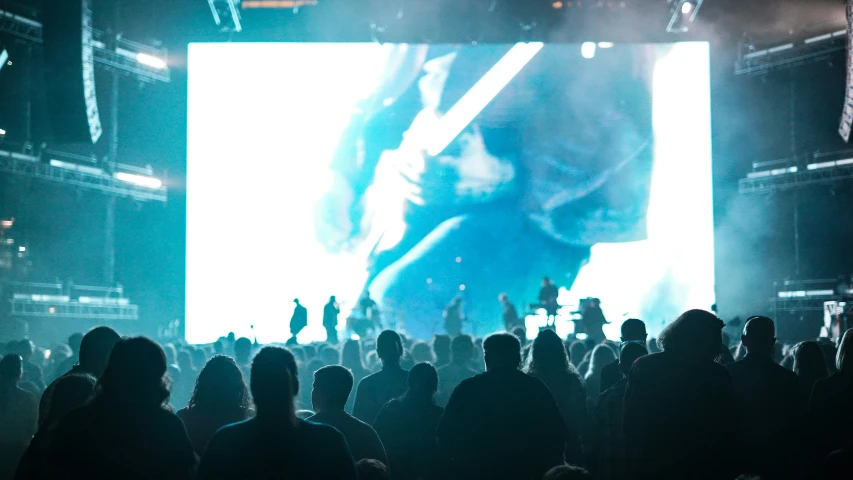 a crowd is standing on the ground watching a large screen