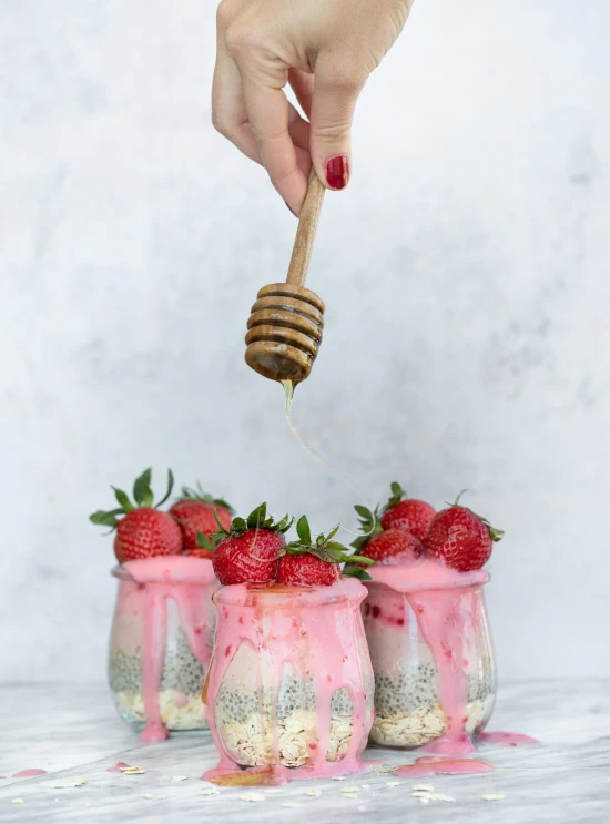 a woman spoons a honey shake with strawberries