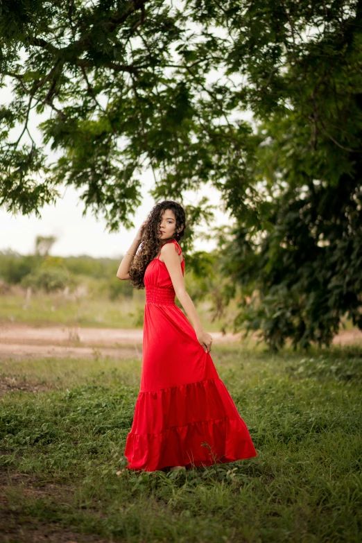 the woman is standing in the grass near the tree