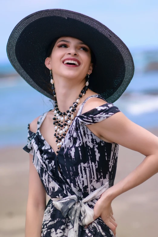 a young woman in a hat standing on the beach