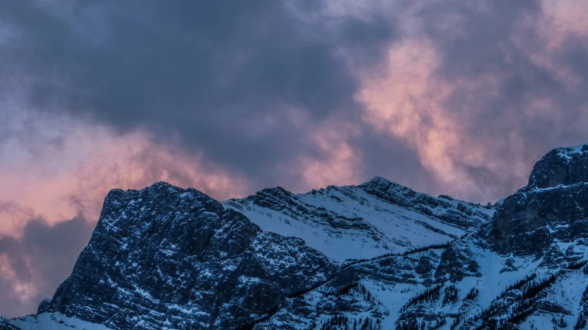 a snow covered mountain against a blue sky at sunset