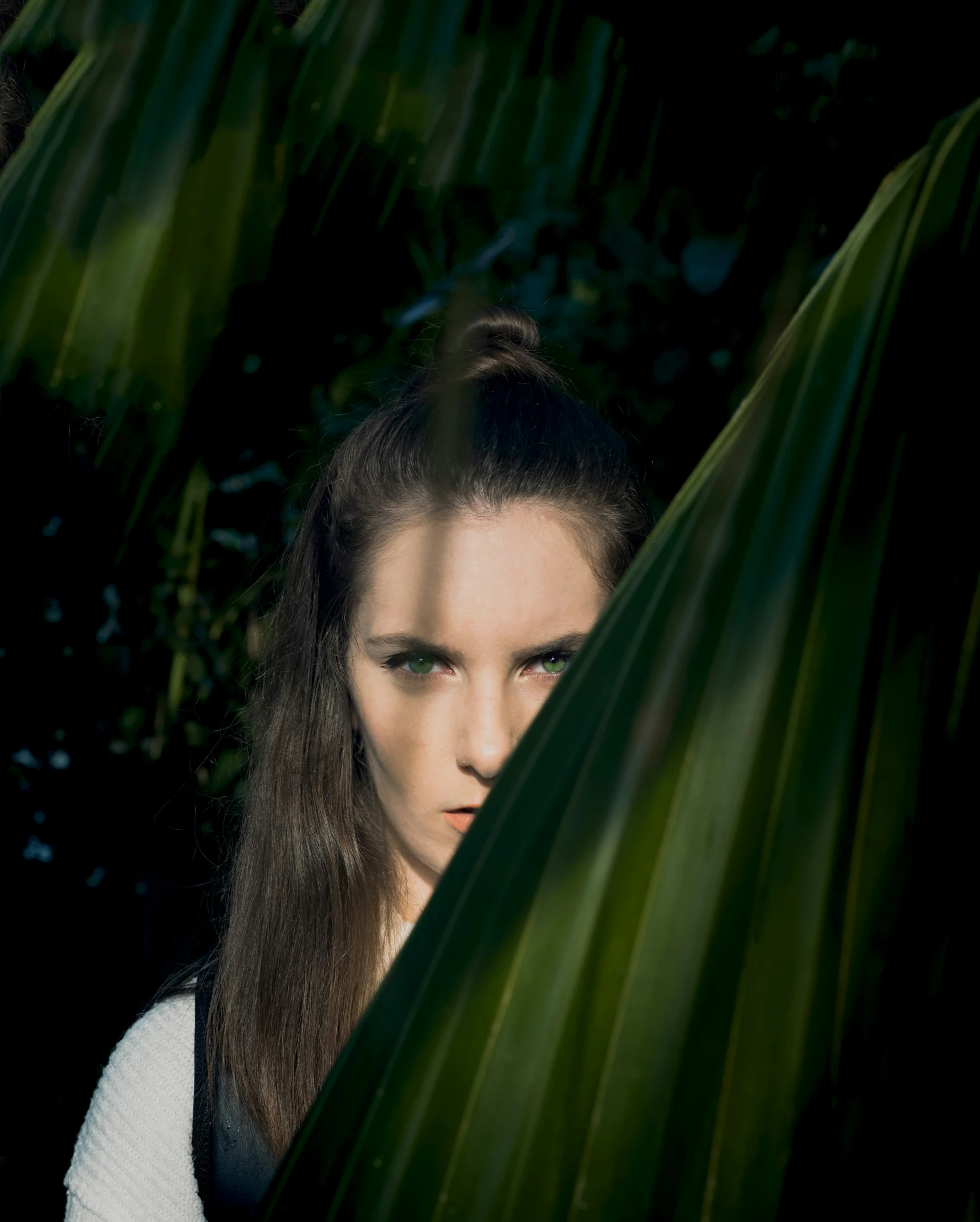 a woman standing between large green leaves in front of her