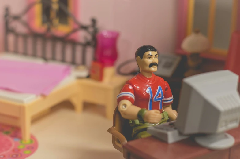 small plastic soccer figure sitting in front of a computer desk