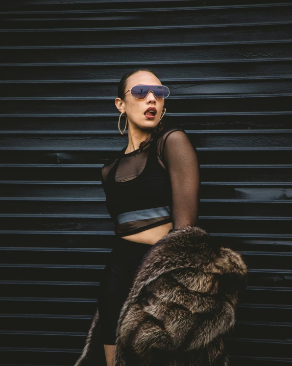 a woman wearing shades stands in front of a wall