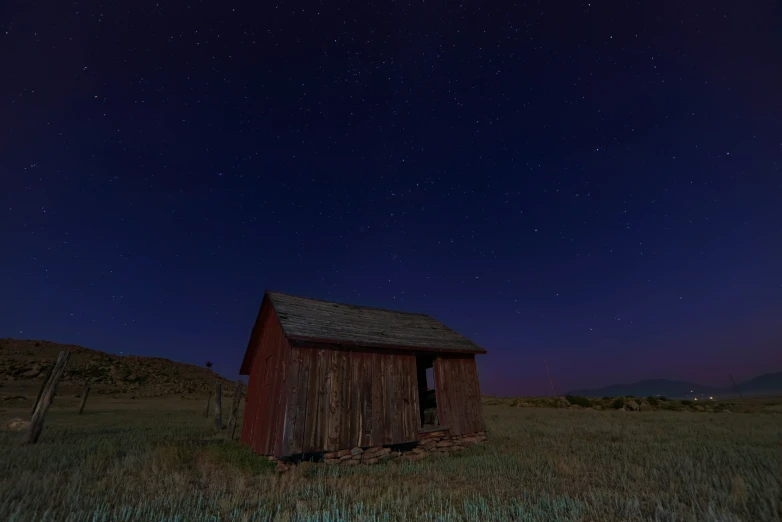 a wooden barn at night time in a field