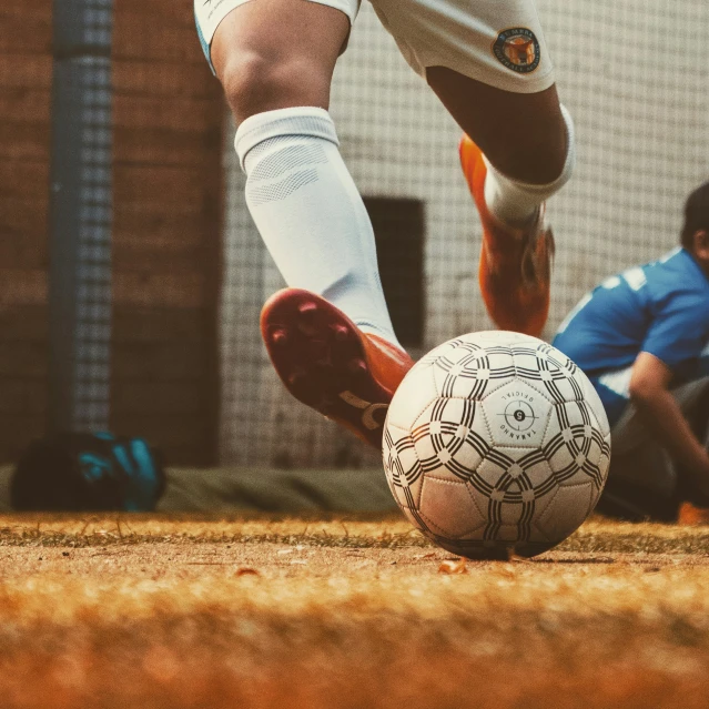 a person is kicking a soccer ball next to another person