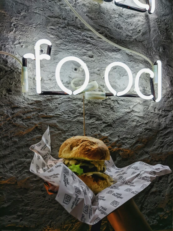 a large hamburger on a wooden stick is in front of the sign