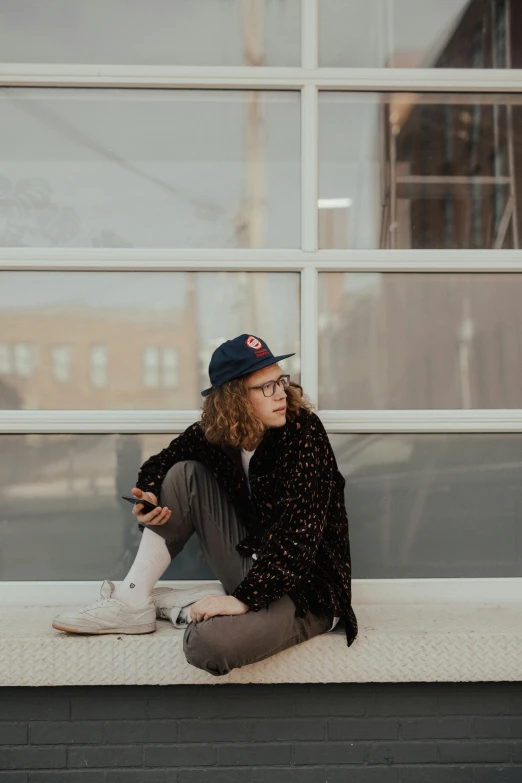 the woman is sitting on the ledge outside with her cigarette in her hand