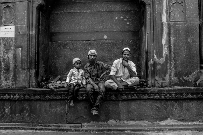 three people sitting on the ledge of an old building