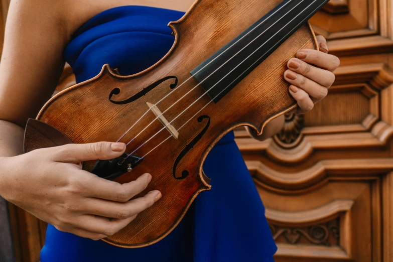 a woman holding onto an antique violin outside