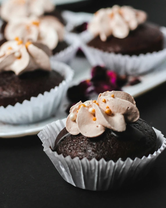 several chocolate cupcakes sit in their trays on a table