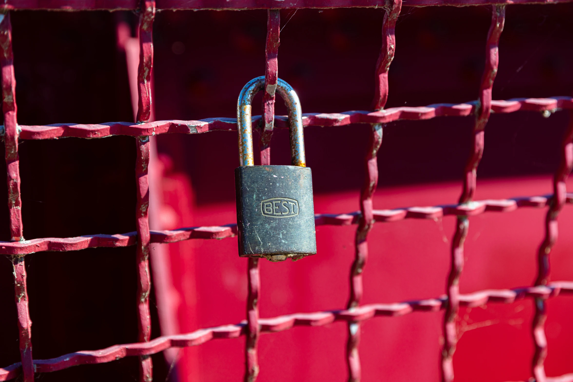 a metal padlock attached to a red metal fence