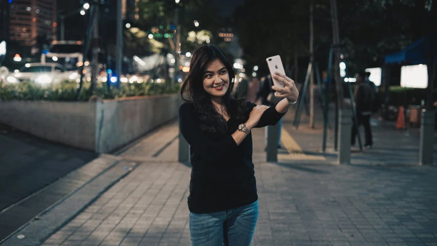 an attractive woman holding a smart phone and taking a po