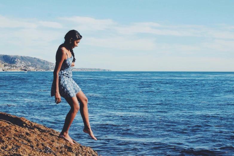 a girl standing on a cliff overlooking the ocean