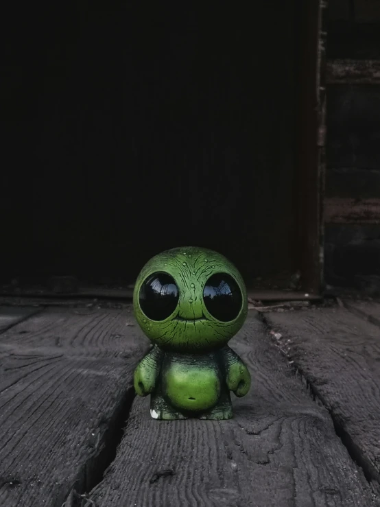 a little, ugly looking toy sitting on wooden planks