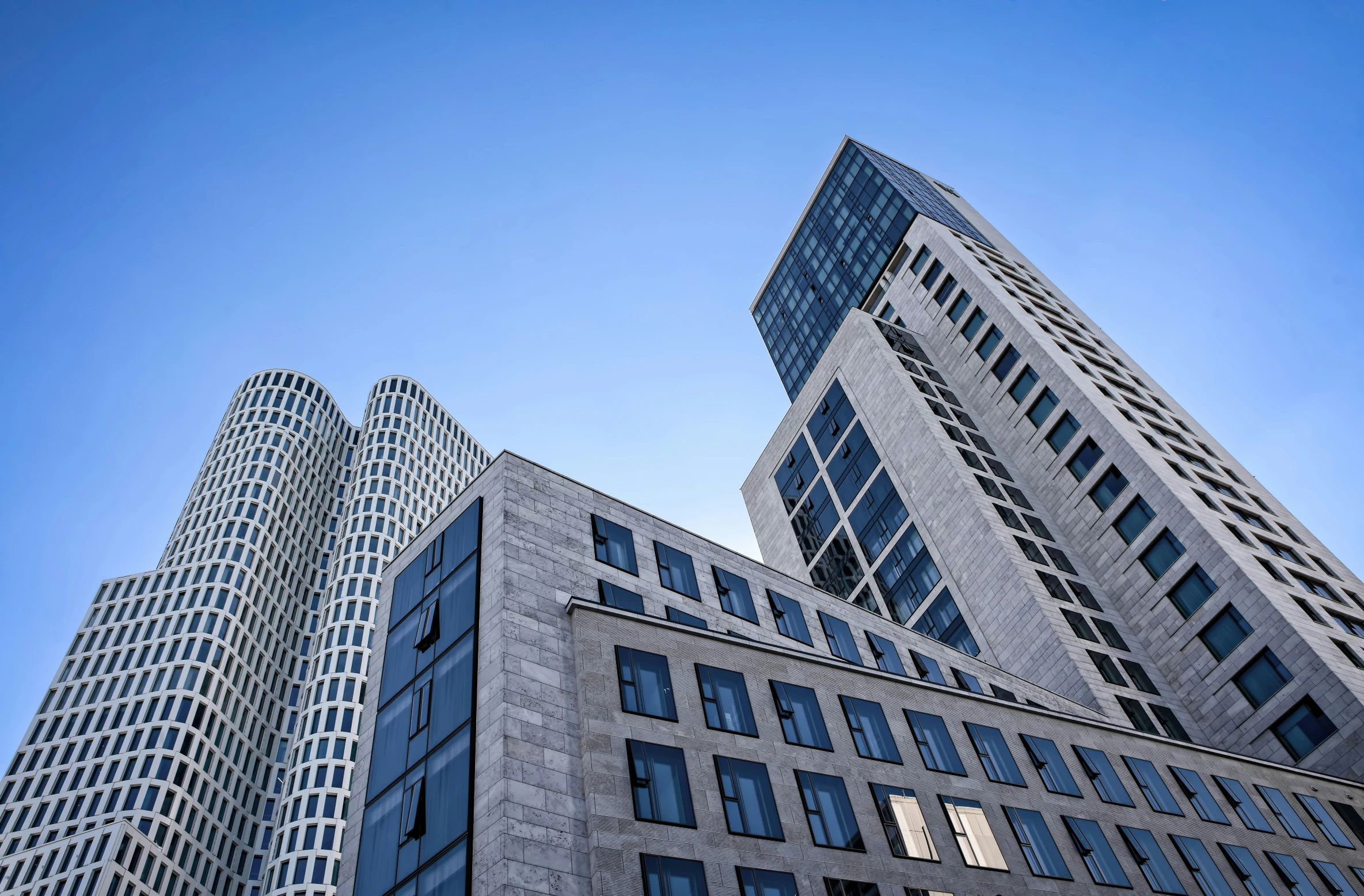 three large grey buildings standing together on a clear day