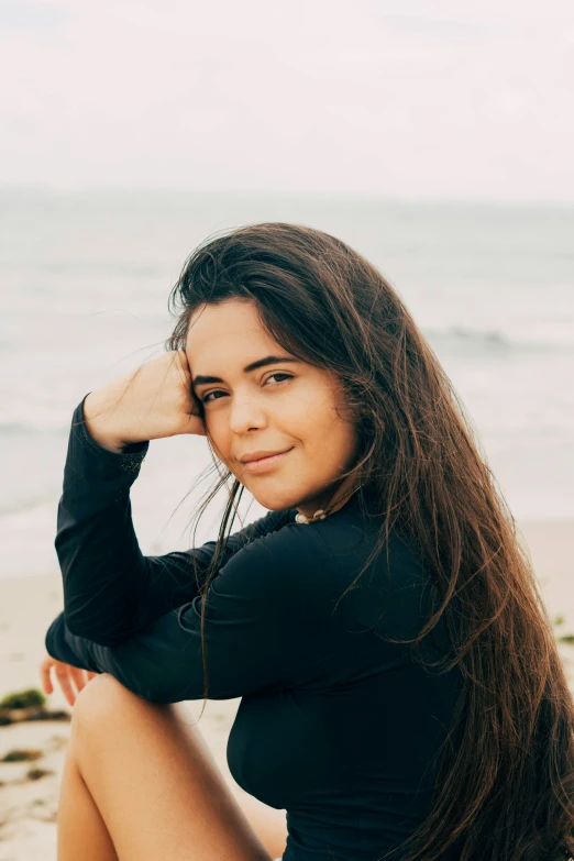 a woman sitting in the sand by the ocean