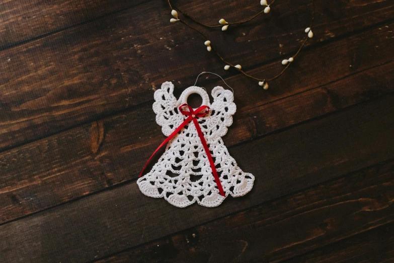 crochet angel decoration hanging on wooden background