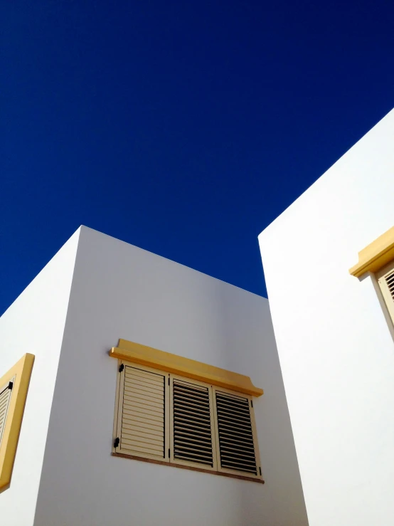 the white building has two windows and two shutters