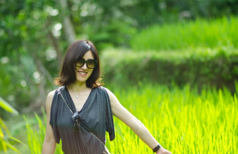 a woman walking through green grass with shades on