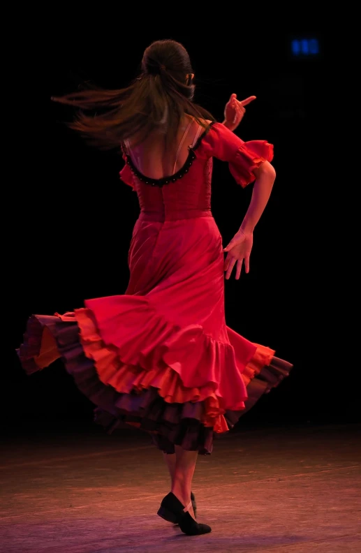 a woman in red dress dancing in the dark