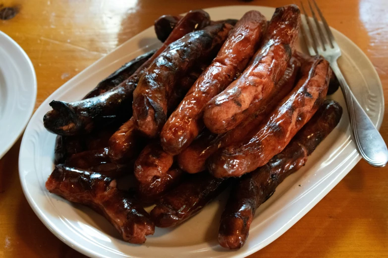 a white plate with sausage sticks and sauce and a fork