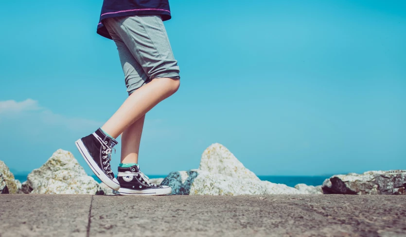 a person walking across a concrete field next to rocks